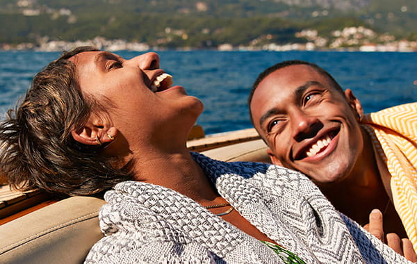Man and woman relaxed and laughing while enjoying a boat ride in a sunny climate.