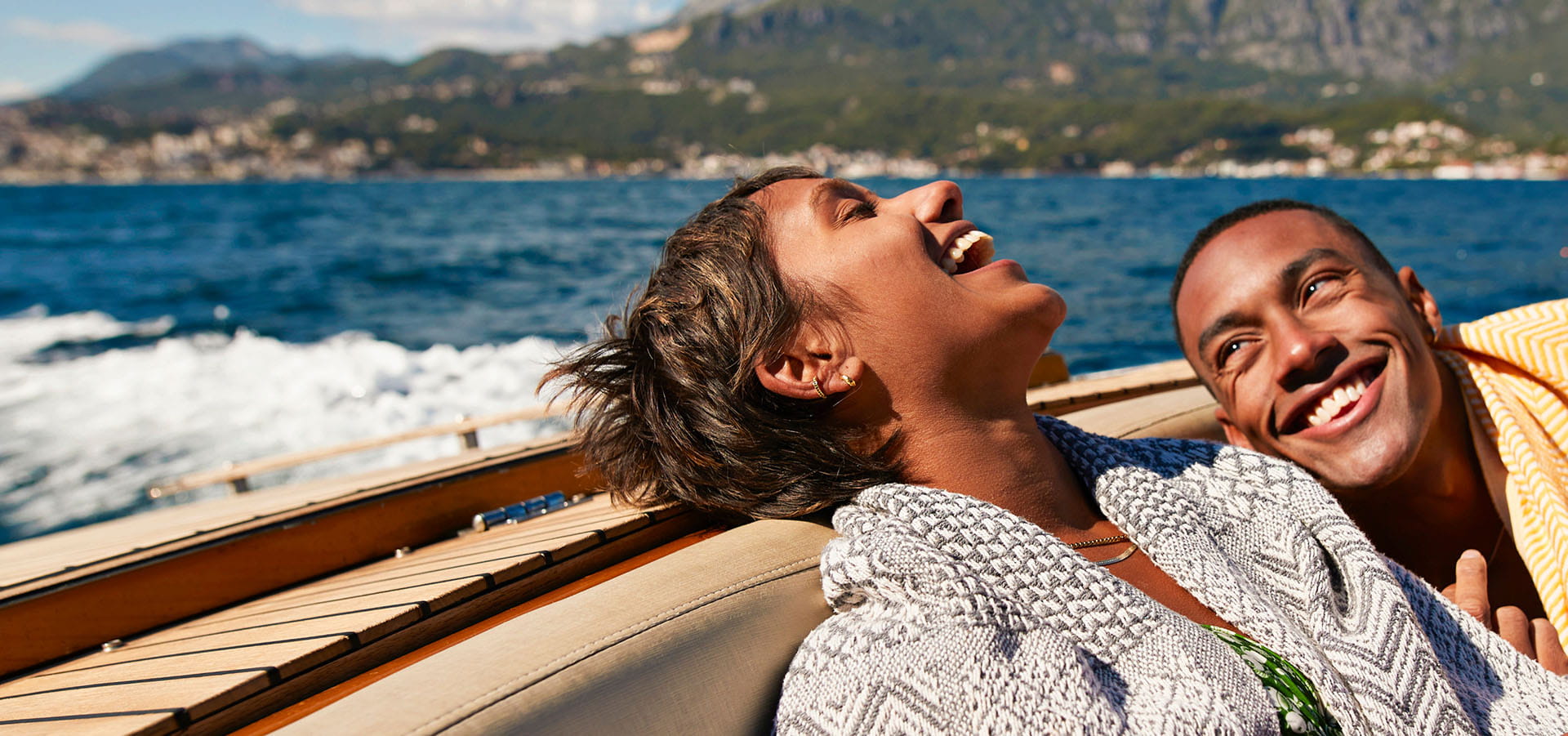 Man and woman relaxed and laughing while enjoying a boat ride in a sunny climate.