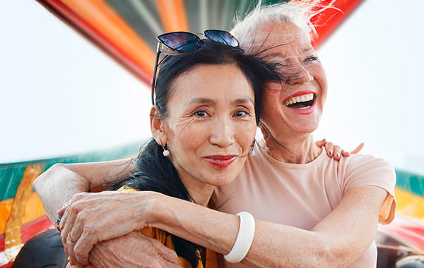 Two female friends embracing in happiness while enjoying a boat ride on holiday.