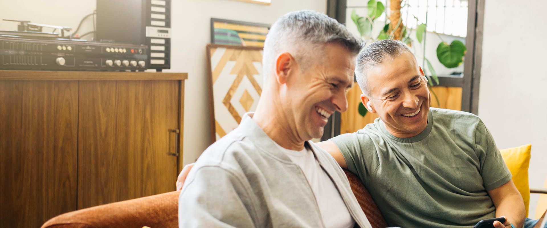 Two men sitting on an orange sofa laughing together