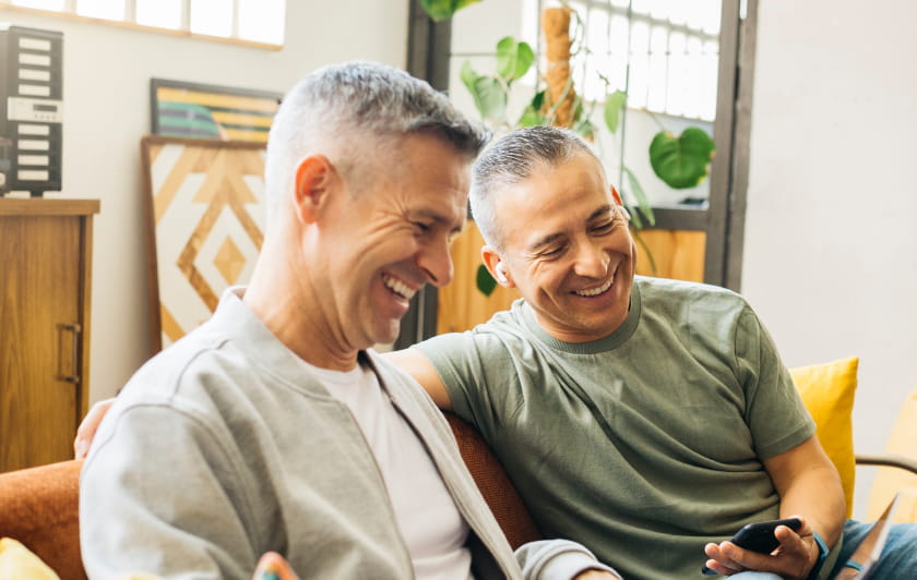 Two men sitting on an orange sofa laughing together
