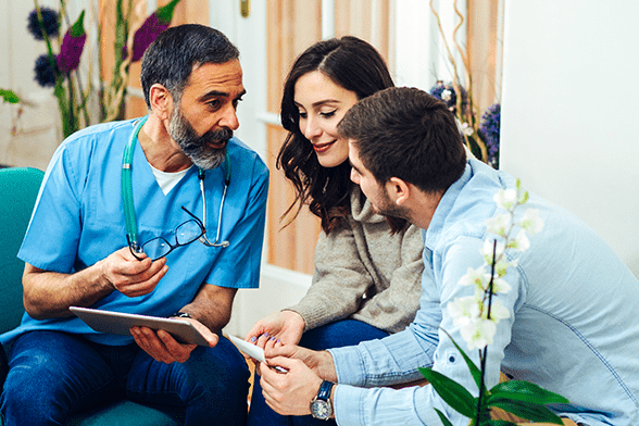 Male doctor discussing a document with a young couple