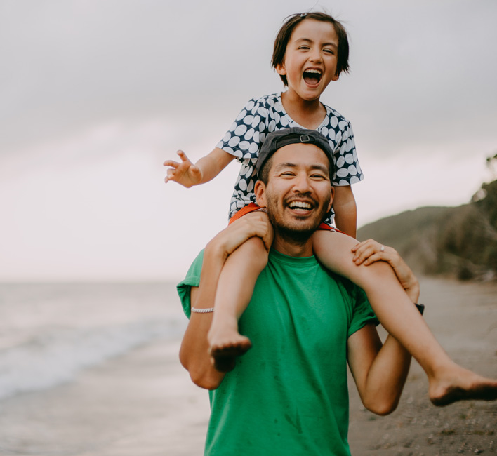 Adult with child on their shoulders at the beach