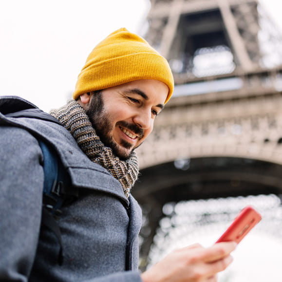 Tourist checking their phone in Paris, standing under the Eiffel Tower