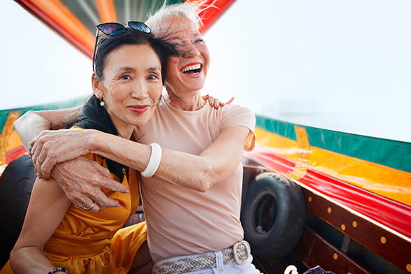 Two female friends embracing in happiness while enjoying a boat ride on holiday.