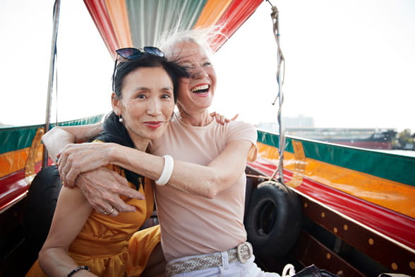 Two female friends embracing in happiness while enjoying a boat ride on holiday.