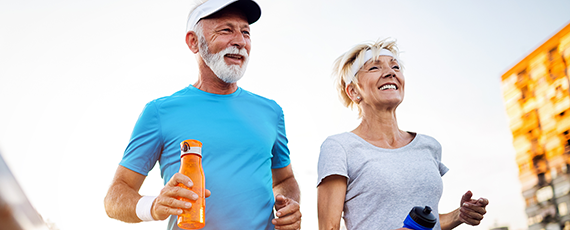 Couple running together outdoors holding water bottles