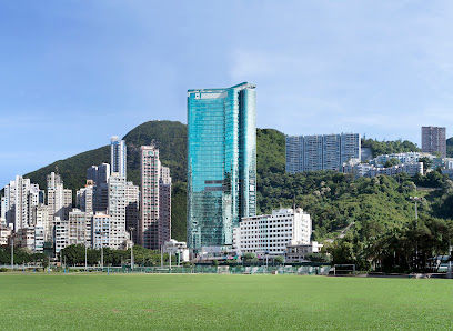 The Hong Kond Sanatorium building in the middle distance, flanked bby other buidlings and with grass parkland in the foreground