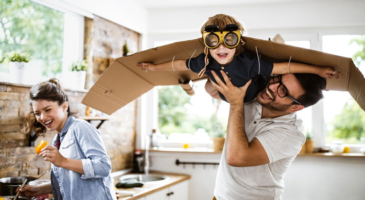 Father playing with their child who has cardboard wings and goggles on